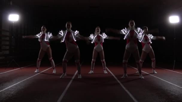 Cheerleaders squadra danza sincronicamente in costumi luminosi — Video Stock