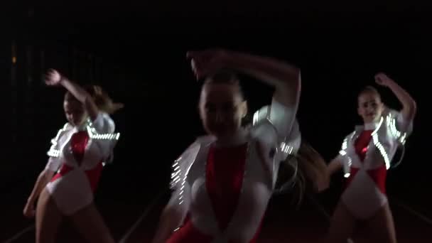 Close up de torcida equipe dançando sincronicamente em trajes luminosos — Vídeo de Stock