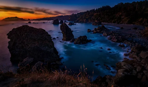 Zonsondergang op een rotsachtige strand — Stockfoto