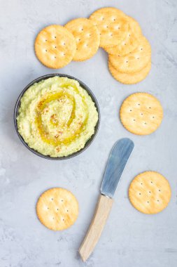 Zeytinyağı, kırmızı biber ve susam serpiştirilmiş sağlıklı avokado humusu kraker, dikey, üst görünüm.