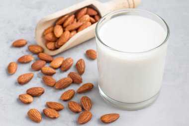 Badem sütü bardakta, bademler arka planda, yatay