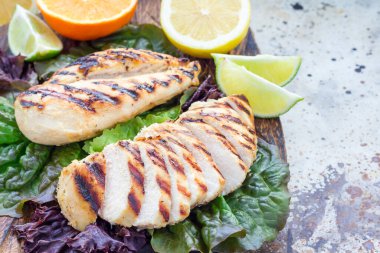 Turunçgiller içinde ızgara tavuk göğsü salata yaprakları ve ahşap kesme tahtası, yatay, kopyalama alanı.