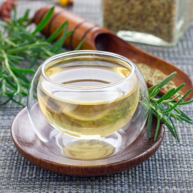 Doğu arka planında cam bir fincanda bitkisel biberiye çayı, kare format