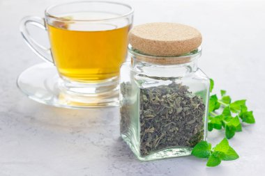 Kavanozda kurutulmuş nane çayı. Arka planda çay, yatay.