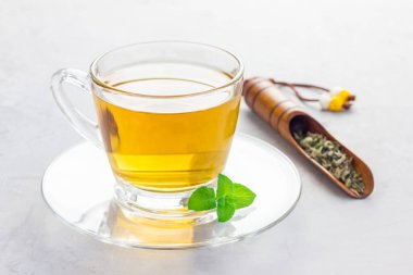 Fonda çay kepçesi olan cam bardakta bitki çayı, yatay.