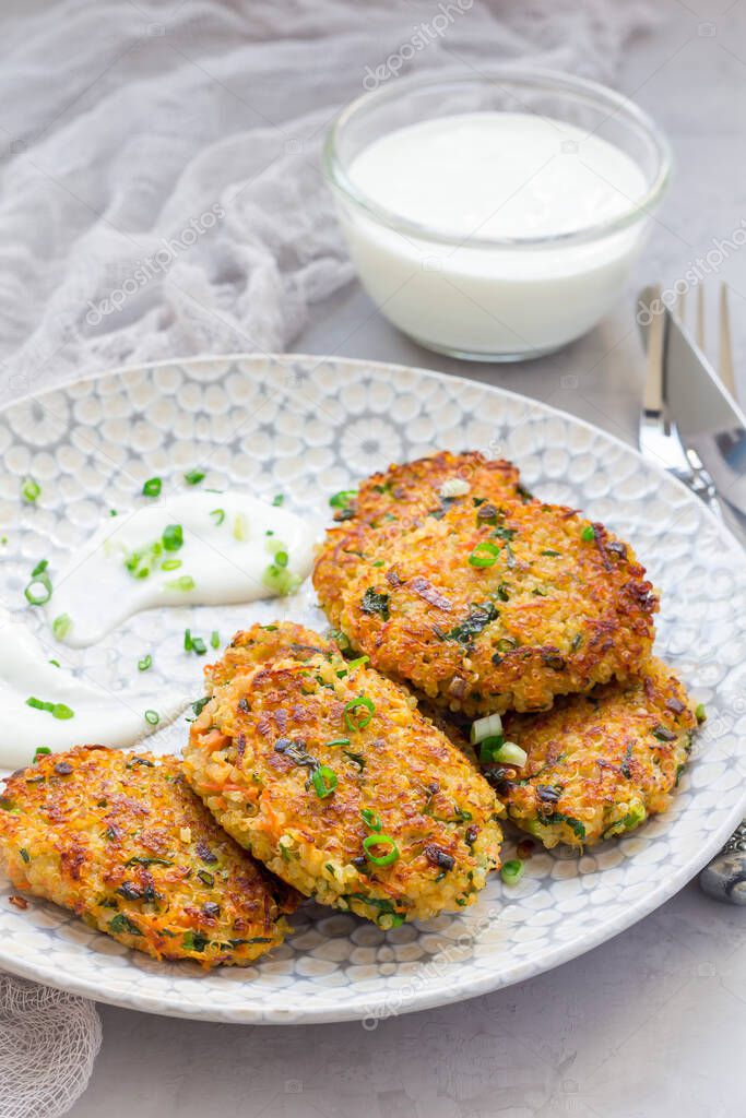 Vegetarian quinoa, carrot, coriander and green onion fritters served with yogurt on plate, vertical