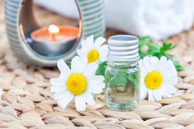 Papatya yağı, örülmüş hasırın üzerindeki camda, spa arka planında, yatay.