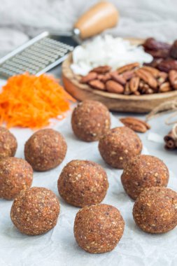 Sağlıklı paleo enerji topları havuç, fındık, hurma ve hindistan cevizi parçacıkları, parşömen üzerinde, dikey