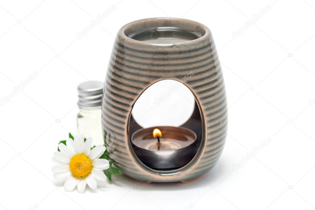 Aroma lamp with chamomile essential oil, glass bottle with oil and fresh flowers on background, isolated on white