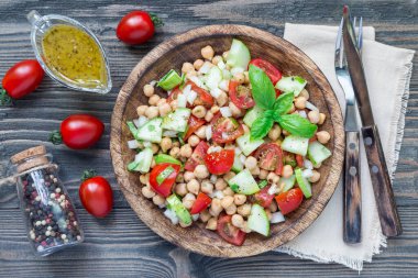Kiraz domatesli nohut salatası, salatalık, fesleğen ve soğanlı narenciye sosu, yatay, üst manzara.