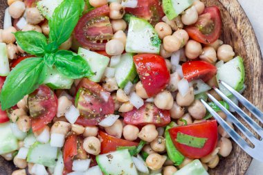 Kiraz domatesli nohut salatası, salatalık, fesleğen ve soğanlı narenciye sosu, yatay, üst manzara, yakın çekim.