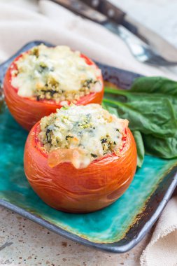 Kino ile doldurulmuş fırında domates ve seramik tabakta erimiş peynirle kaplı ıspanak.
