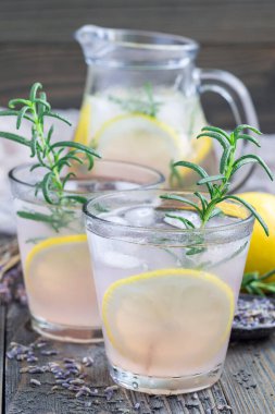 Ev yapımı lavantalı limonata, taze limon ve ahşap arka planda biberiye, dikey.
