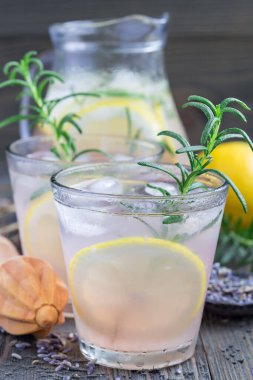 Ev yapımı lavantalı limonata, taze limon ve ahşap arka planda biberiye, dikey.