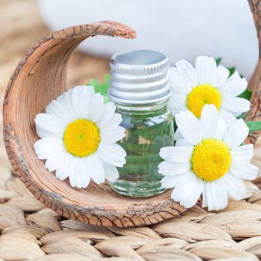 Papatya yağı, örülmüş hasırın üzerindeki camda, kaplıca arka planında, kare biçiminde.