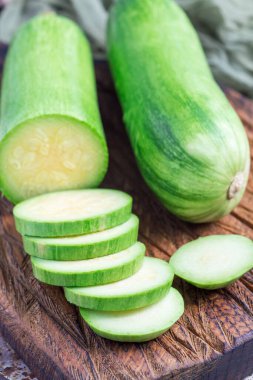 Sebze yemeği hazırlıyorum. Kabak ve kabak tahta bir kesme tahtasında dikey dilimler.