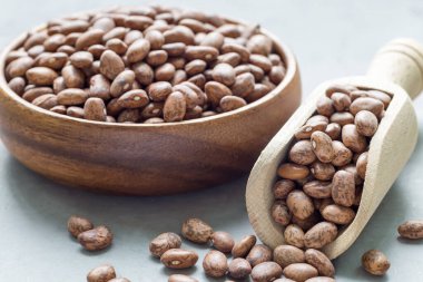 Ahşap kasede pişmemiş kuru fasulye ve kepçenin içinde, yatay.