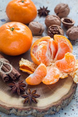 Noel arkaplanı. Aromatik kış baharatları, cevizler ve mandalinalar tahta kütüğün üzerinde, dikey