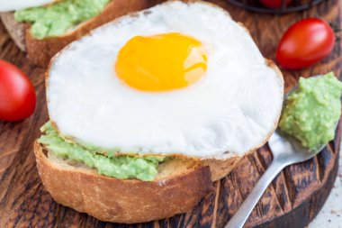 Avokado püresi ve kızarmış yumurtalı sandviç, kızarmış ekmek, yatay ve yakın plan.