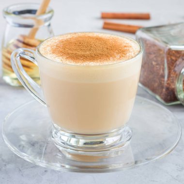 Sağlıklı, tarçınlı, cam bardakta ve arka plandaki malzemelerle kaplı kırmızı latte.