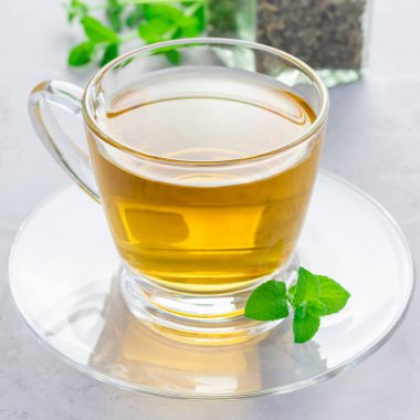 Cam bardakta naneli çay, arka planda taze nane, kare şeklinde.
