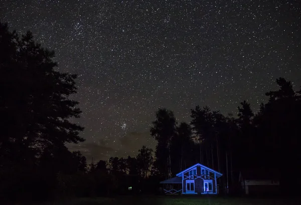 Yö tähtitaivas kohtaus valaistu mökki — kuvapankkivalokuva