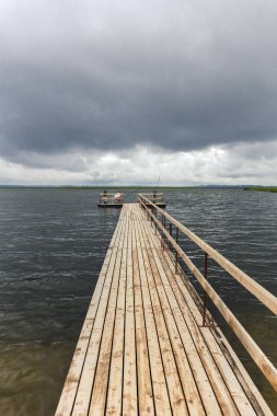 Ahşap iskele ve balıkçılar ile dramatik peyzaj