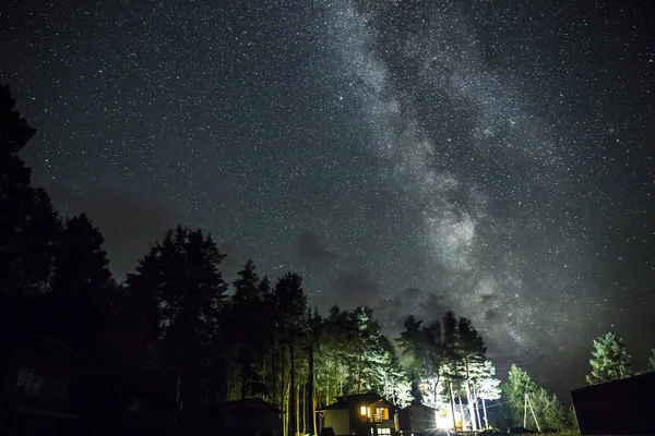 Nattstjernehimmelen med opplyst hytte – stockfoto