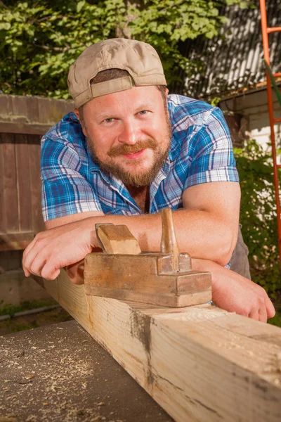Carprnters portrait with wooden plank and plane smiling Royalty Free Stock Images