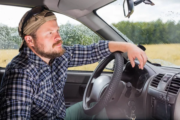 Bebaarde man zit in de cabine van een auto — Stockfoto