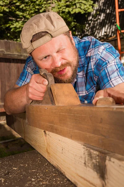 Carpenter chipping the wooden plank Stock Picture