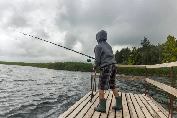 Dospívající chlapec rybolov na dřevěném molu — Stock fotografie