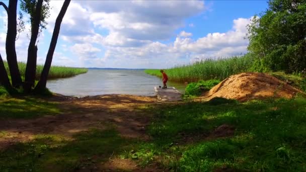 Boy playing on green grass lake shore — Stock Video