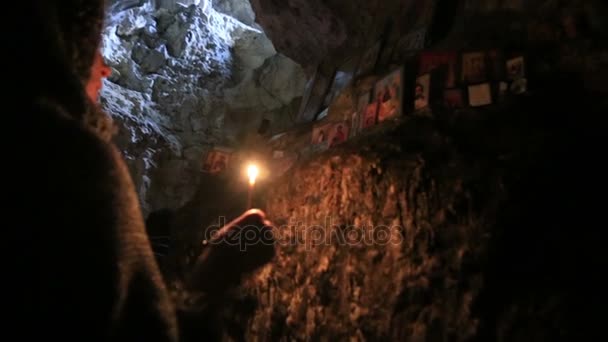 Mulher com vela uma frente os ícones em Simon the Zealots Simon Kananaios caverna na Abcásia — Vídeo de Stock