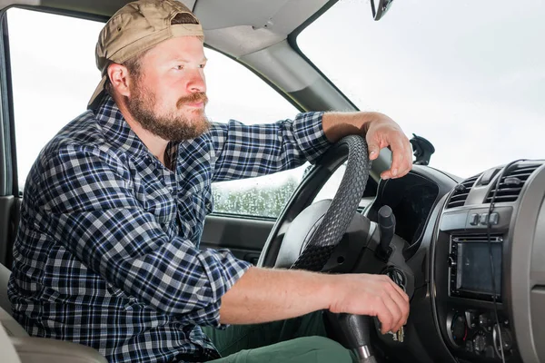 Bebaarde man zit in de cabine van een auto — Stockfoto