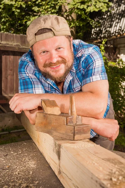 Carprnters portrait with wooden plank and plane smiling Royalty Free Stock Images