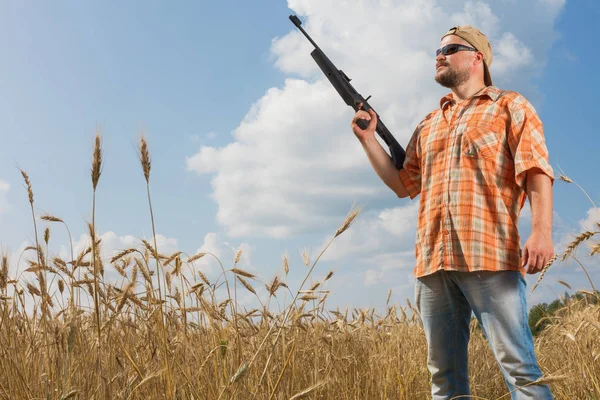 Охотник в кепке и солнцезащитных очках нацелил пистолет на поле — стоковое фото