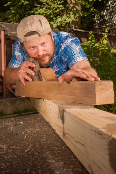 Carpenter chipping the wooden plank Stock Image