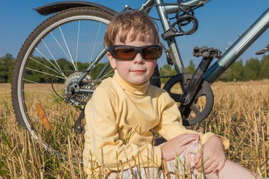 Neşeli çocuk bisiklet ile oturan güneş gözlüğü