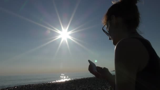 Молодая красивая женщина на пляже с помощью мобильного телефона — стоковое видео