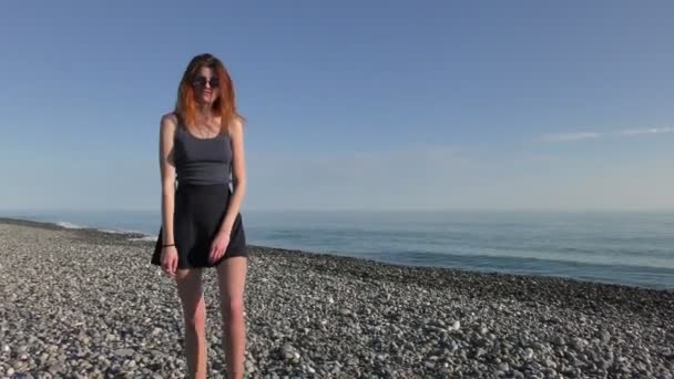 Young attractive woman in sunglasses on the pebble beach — Stock Video
