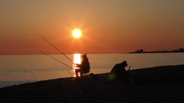 Mooie scène met visser silhouet met rod zittend op zee strand — Stockvideo