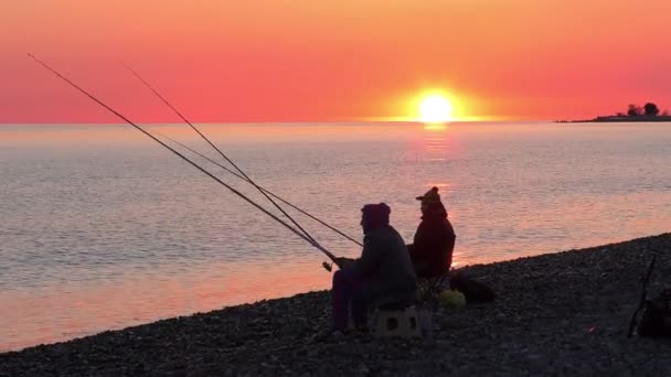 Όμορφη σκηνή με ψαρά σιλουέτα με ράβδο που κάθεται στην παραλία της θάλασσας — Αρχείο Βίντεο