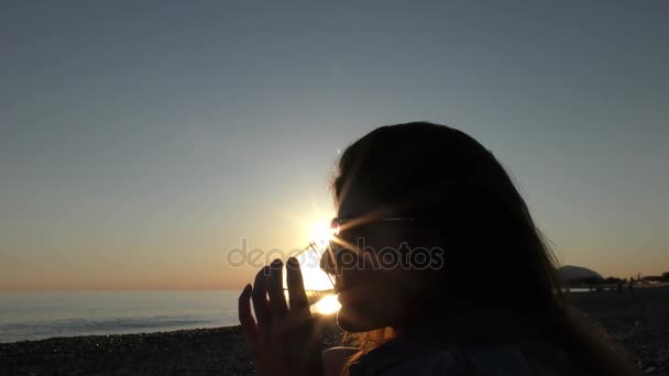 Νέα ελκυστική γυναίκα στην παραλία στο ηλιοβασίλεμα πίνοντας από γυαλί — Αρχείο Βίντεο