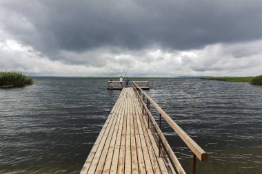 Ahşap iskele ve balıkçılar ile dramatik peyzaj