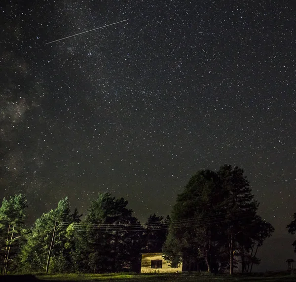 Yö tähtitaivas kohtaus valaistu mökki — kuvapankkivalokuva