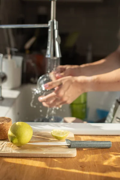 close up of woman hands washing dish bottle glass. wash the dishes oncept. modern kitchen. economical water consumption concept. clear water pouring from faucet. water crisis problem worldwide