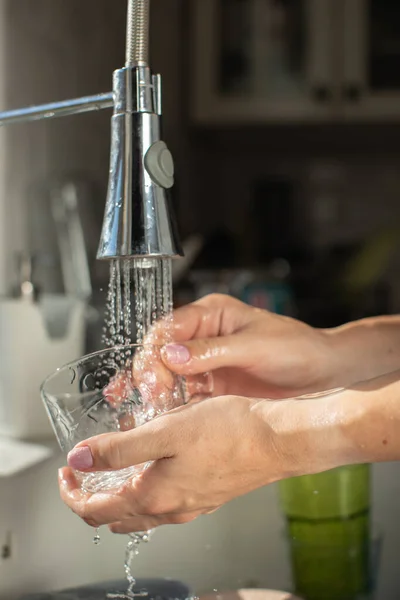 waterproof watch concept. close up of woman hands washing glass cup. wash the dishes concept