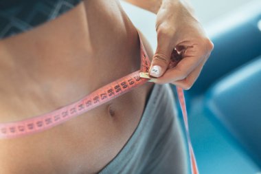 Mükemmel bir karın ağrısı. Vücudunda su şişesi olan bir kız. sağlıklı yaşam tarzı konsepti. Kız evde çalışıyor. Spor beli. Forma gir. Spor kızı. Kilo veren kadın