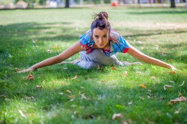 Genç kadın parkta yoga yapıyor. 